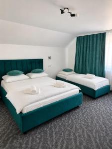 two beds in a room with green and white at Denisa & Rares in Tăşnad