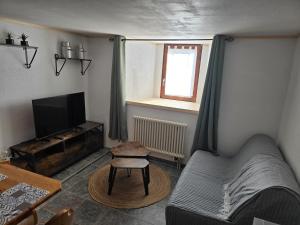 a living room with a couch and a television at Le Repos du Jorat in Saint-Maurice