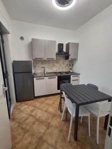 a kitchen with a table and a black table and chairs at pomelia holiday house in Riposto +10 photos