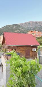 a wooden building with a red roof and some plants at Vikendica za odmor in Dobra Voda