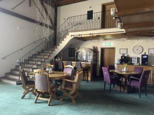 a dining room with tables and chairs and a staircase at Hotel Eulenhof in Gransdorf