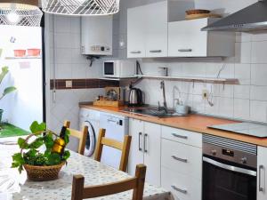 a kitchen with white cabinets and a table with a plant on it at Casa Beatriz in Cambados