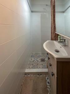 a white bathroom with a sink and a shower at Tommy's Cottage in Harta +23 photos