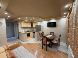 a living room with a table and chairs and a kitchen at Sunset Apartman Obrenovac,Centar in Obrenovac