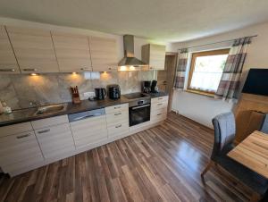 a kitchen with white cabinets and a wooden floor at Lipperhof in Schwendau