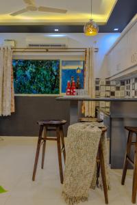 a kitchen with two stools and a counter and a window at 2bhk Excella Apartment at Vagator in Vagator