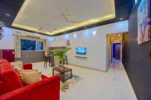a living room with a red couch and a table at 2bhk Excella Apartment at Vagator in Vagator