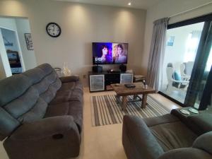 a living room with two couches and a flat screen tv at Intimi2 in Yzerfontein