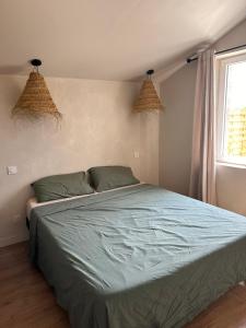 a bedroom with a bed with blue sheets and a window at La parenthèse in Lagrave