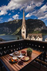 a table with plates of food on a balcony with a church at Franz 38 - Appartement Hallstatt in Hallstatt