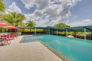 a swimming pool with tables and chairs and umbrellas at Hill Garden Boutique Resort in San Ignacio