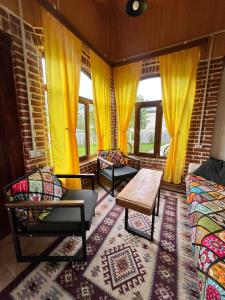 a living room with yellow curtains and a table and chairs at Marisi Cottage - კოტეჯი მარისი in Ambrolauri +11 photos
