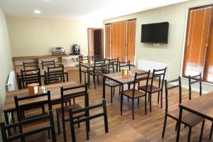 a dining room with tables and chairs and a flat screen tv at Hotel Kvarlis Mtebi in Kvareli
