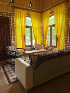 a living room with a couch and yellow curtains at Marisi Cottage - კოტეჯი მარისი in Ambrolauri