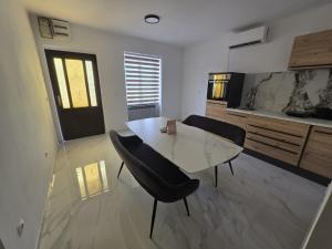 a kitchen with a white table and two black chairs at Smiljana 36 in Klimno +28 photos