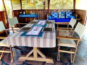 a table with four chairs and a blue couch at 2 Authentic Mara Bush Cottages in Sekenani +29 photos