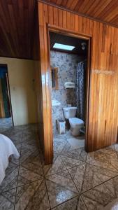 a bathroom with a toilet and a stone wall at Monteverde Monkey Hostel in Monteverde Costa Rica
