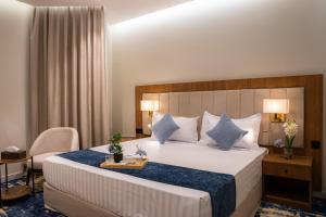a hotel room with a large bed and a chair at H SAM Hotel in Taif