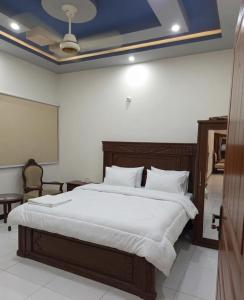 a bedroom with a large bed with white sheets at Nursery Lodge Guest House in Karachi