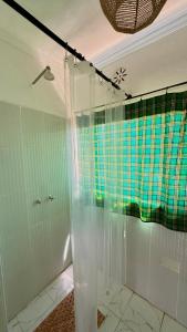 a bathroom with a shower with a plaid shower curtain at 2 Authentic Mara Bush Cottages in Sekenani