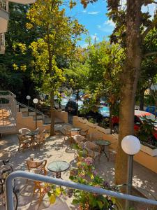 a patio with tables and chairs and a tree at K2 Hotel in Cattolica