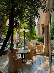 eine Terrasse mit Tisch und Stühlen und Bäumen in der Unterkunft Hotel Caracas in Cattolica