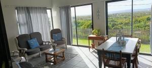 a living room with a table and chairs and large windows at Intimi2 in Yzerfontein
