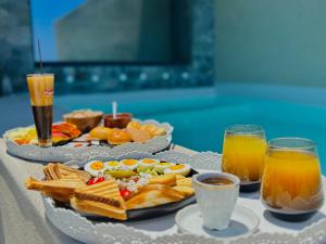 a table with two plates of food and two glasses of orange juice at Bevimar Suites with Private Pool and Non Heated Jacuzzi in Santorini