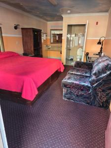 a bedroom with a red bed and a couch at Evans Motel in Maywood