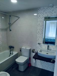 a bathroom with a toilet and a tub and a sink at apartamento victor in Cee
