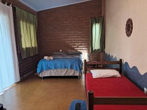 a bedroom with two beds and a brick wall at Vila Chapada Alta - Chapada dos Veadeiros in Alto Paraíso de Goiás