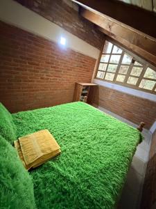 a large green bed in a room with a brick wall at Cabaña La Joyita By GEstores in Huasca de Ocampo
