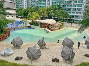a swimming pool with umbrellas and people in the water at SM Bicutan Staycation by Urban Suite in Manila