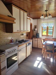 eine Küche mit weißen Geräten und einem Tisch mit Stühlen in der Unterkunft Omas Paradies in Größing