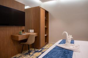 a hotel room with a desk and a bed with a swan towel at H SAM Hotel in Taif