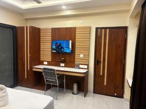 a hotel room with a desk with a tv on the wall at Asusss International in New Digha