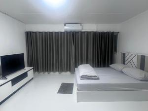 a white room with a bed and a television at อิมแพค เมืองทองธานี c8 ชั้น 13 ห้องพักรายวัน in Thung Si Kan