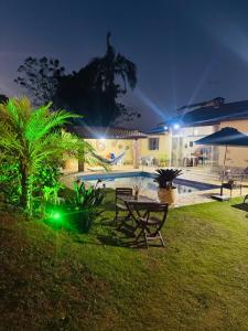a backyard with a table and a pool at night at Cintia Barrozo Nunes in Ibiúna