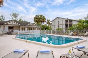 a swimming pool with tables and chairs next to a building at Convenient & Inviting - Fully-Equipped 2BD Condo in Gainesville