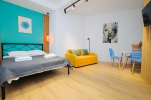 a bedroom with a bed and a yellow chair and a table at M Boutique Aparthotel in Tbilisi City +21 photos