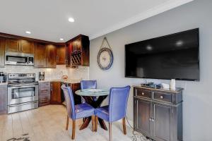 a kitchen with a table with blue chairs and a flat screen tv at HH Beach & Tennis 226C in Hilton Head Island