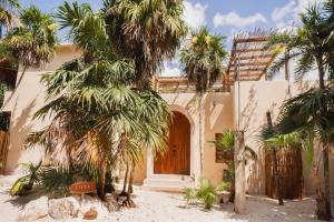 a house with palm trees and a wooden door at Villa Hydra Private Villa with Rooftop Pool in El Cuyo