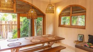 a dining room with a wooden table and windows at Villa Hydra Private Villa with Rooftop Pool in El Cuyo