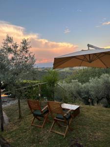 two chairs and a table and an umbrella at Le Case Gialle Resort in Gualdo Cattaneo