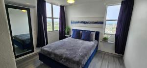 a bedroom with a bed with blue pillows and windows at Oceanfront 3-bedroom Sub-Penthouse in Luquillo PR in Luquillo