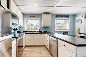 a kitchen with white cabinets and blue walls at Breath'n Easy in Edisto Beach +31 photos