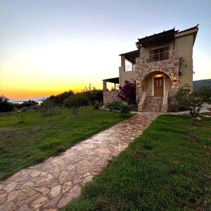 a house on a hill with the sunset in the background at "Villa Othon-Leni" - Panoramic Sea View & Traditional Luxury in Paralia Demonias +67 photos