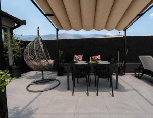 a patio with a black table and chairs and a swing at Villa Pantheon Mostar in Blagaj