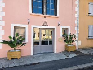 a pink building with a door and two plants at Gite de yaya in Cousance
