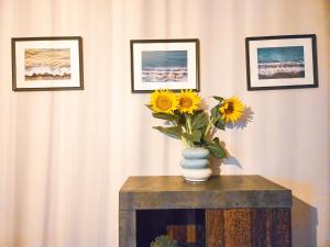a vase of sunflowers on a table with pictures at Guest House Medusa - Old town in Pomorie